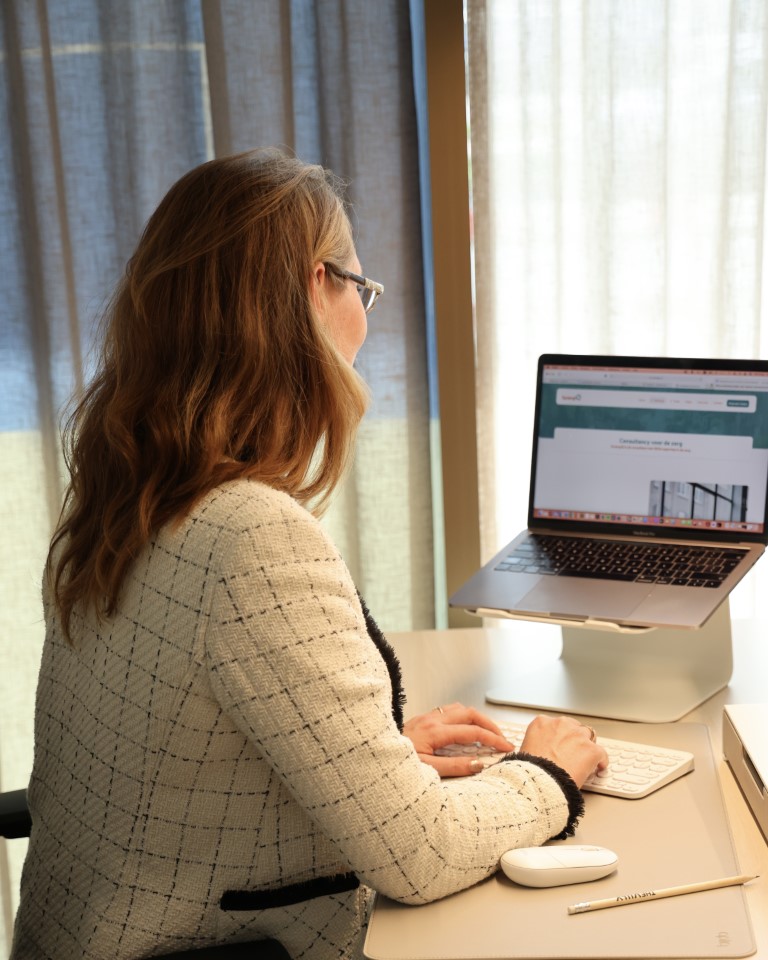 Jessica Leeuwenburg van SynergiQ kijkend in de camera met een laptop